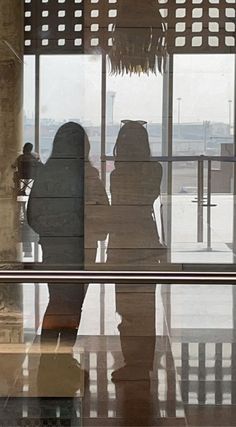 two people are standing in front of a window