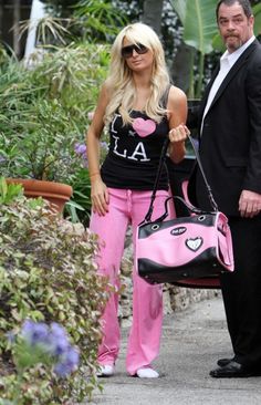 the man and woman are walking down the sidewalk with their pink handbags in front of them