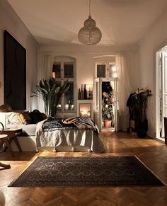 a bedroom with wood flooring and white walls is lit by lights from the windows