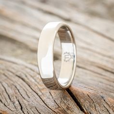 the wedding ring is sitting on top of a wooden plank surface, with an inscription engraved in it