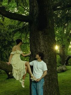 a man and woman sitting on a tree in the park, one holding onto another