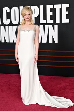 a woman in a white dress standing on a red carpet