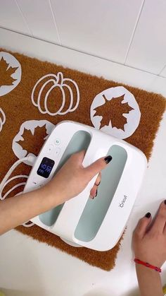 a woman is using a scale to measure the weight on a mat with fall leaves and pumpkins