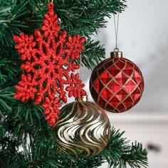 two red and gold ornaments hanging from a christmas tree