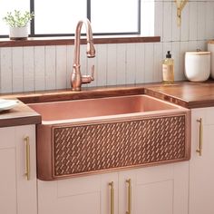 a kitchen sink with copper faucet and wooden counter tops