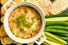 a white bowl filled with dip surrounded by crackers and celery