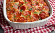 a pepperoni and cheese casserole in a white dish on a checkered cloth