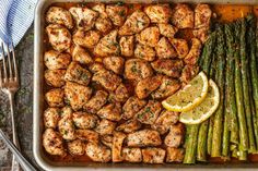 chicken, asparagus and lemons in a baking dish with a fork on the side