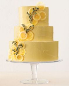 a three tiered cake with lemons and herbs on top