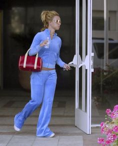 a woman in blue is walking out of a building with her handbag on the door