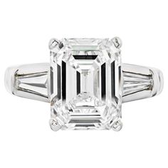 Stunning ring when you want to show up! Mounted with an impressive 4 carat Emerald Cut Diamond that is mounted in platinum accented by baguette cuts. The Center diamond is a certified K/VS2 GIA stone. Three-stone diamond engagement rings have always been a classic. Especially in platinum! We noticed that this center diamond looks bigger than a typical 4 carat and the savings you are getting shopping in K color category are just unbelievable. Beautiful ring that delivers a lot of wow factor! Beli Luxury Vvs Clarity Baguette Cut Emerald Ring, Luxury Emerald-cut Diamond Engagement Ring, Luxury Diamond White Baguette Cut Emerald Ring, Baguettes Engagement Ring, Luxury Emerald-cut Platinum Ring, Luxury Emerald-cut Diamond White Diamond Ring, Tiffany Engagement, Pear Cut Diamond Ring, Brilliant Cut Diamond Ring