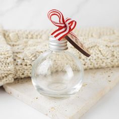 a small glass bottle with a red and white ribbon on it