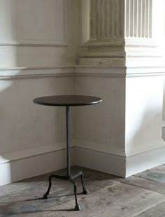 a small table sitting in the corner of a room next to a wall with columns