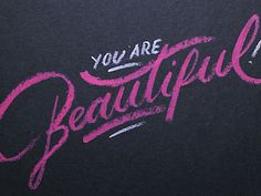 the words you are beautiful written in pink chalk on a black background with white writing