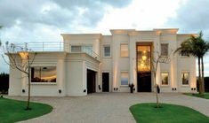 a large white house with palm trees in the front yard and walkway leading up to it