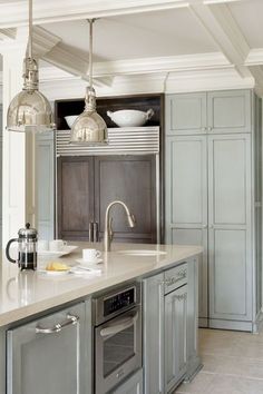 a kitchen with gray cabinets and white counter tops, an oven and sink in the center