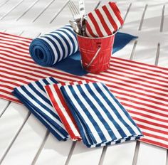 red, white and blue striped table cloths with utensils on them next to a cup