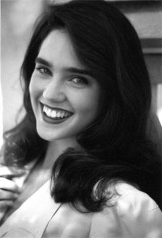 a black and white photo of a woman with long dark hair smiling at the camera