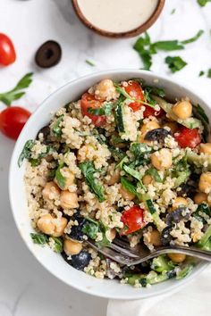 a white bowl filled with couscous, beans and vegetables next to a spoon