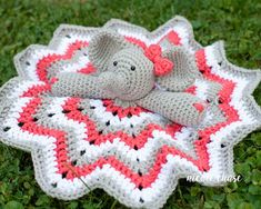 a crocheted elephant laying on top of a blanket in the grass with it's eyes closed