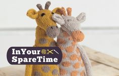 two knitted giraffes standing next to each other on a wooden surface