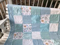 a blue and white quilted blanket sitting on top of a wooden bench