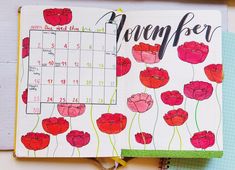 an open planner with red flowers and the word november written in black ink on it