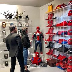 two men looking at spider - man action figures in a display case with antlers on the wall