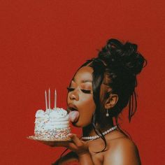 a woman blowing out candles on a cake with white frosting and sprinkles