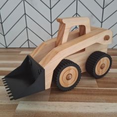 a wooden toy truck with a shovel on the front sitting on top of a hard wood floor