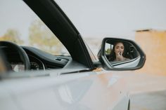 a woman is seen in the side mirror of a car