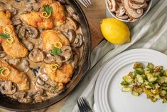 a skillet filled with chicken and mushrooms next to a plate of broccoli