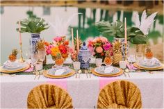 the table is set with pineapples, orange flowers and other tropical items for an elegant dinner