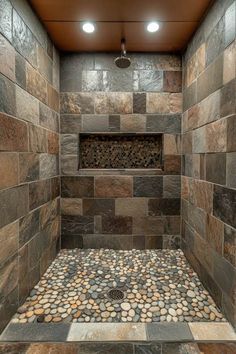 a walk in shower with stone flooring and tile on the walls, along with two recessed lights