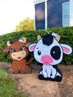 two paper cut out animals sitting next to each other on top of a dirt ground