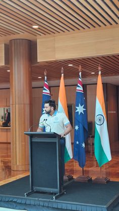 a man standing at a podium in front of flags