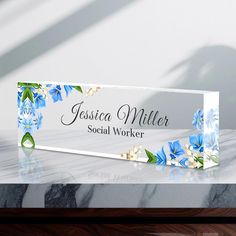 a wooden sign with blue flowers on it sitting on top of a marble countertop