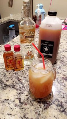 bottles of liquor sit on a counter top next to a glass with a straw in it