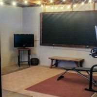 a room with a blackboard, exercise equipment and lights on the ceiling in front of it