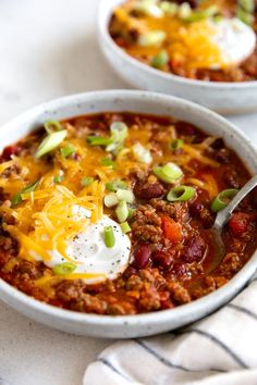 two white bowls filled with chili and cheese