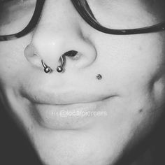 a close up of a person wearing glasses with a nose piercing on their left side