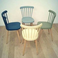 four chairs sitting on top of a wooden floor next to each other in different colors