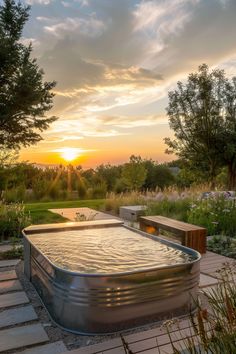 an outdoor hot tub in the middle of a garden at sunset, with trees and flowers around it