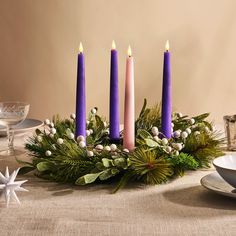 a table topped with purple candles and greenery