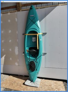 a blue kayak sitting on top of a wooden platform next to a white wall