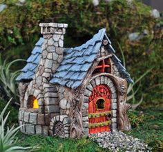 a small house made out of rocks with a red door and window on the front