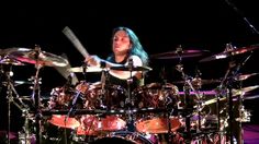 a woman with blue hair playing drums on stage