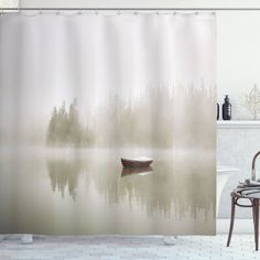 a boat floating on top of a lake next to a lush green forest covered in fog