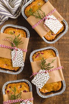 four tins filled with baked goods on top of a wooden table