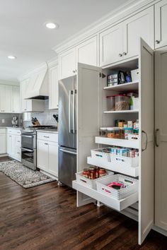 an organized pantry in the middle of a kitchen with white cabinets and wood flooring